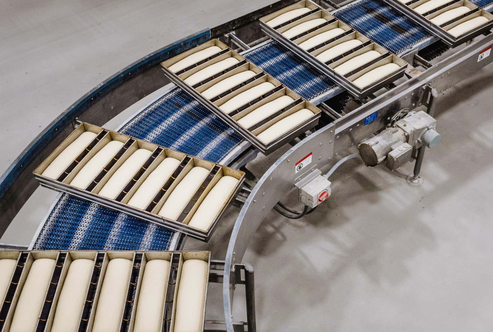 conveyor of bread dough in pans on their way to the oven